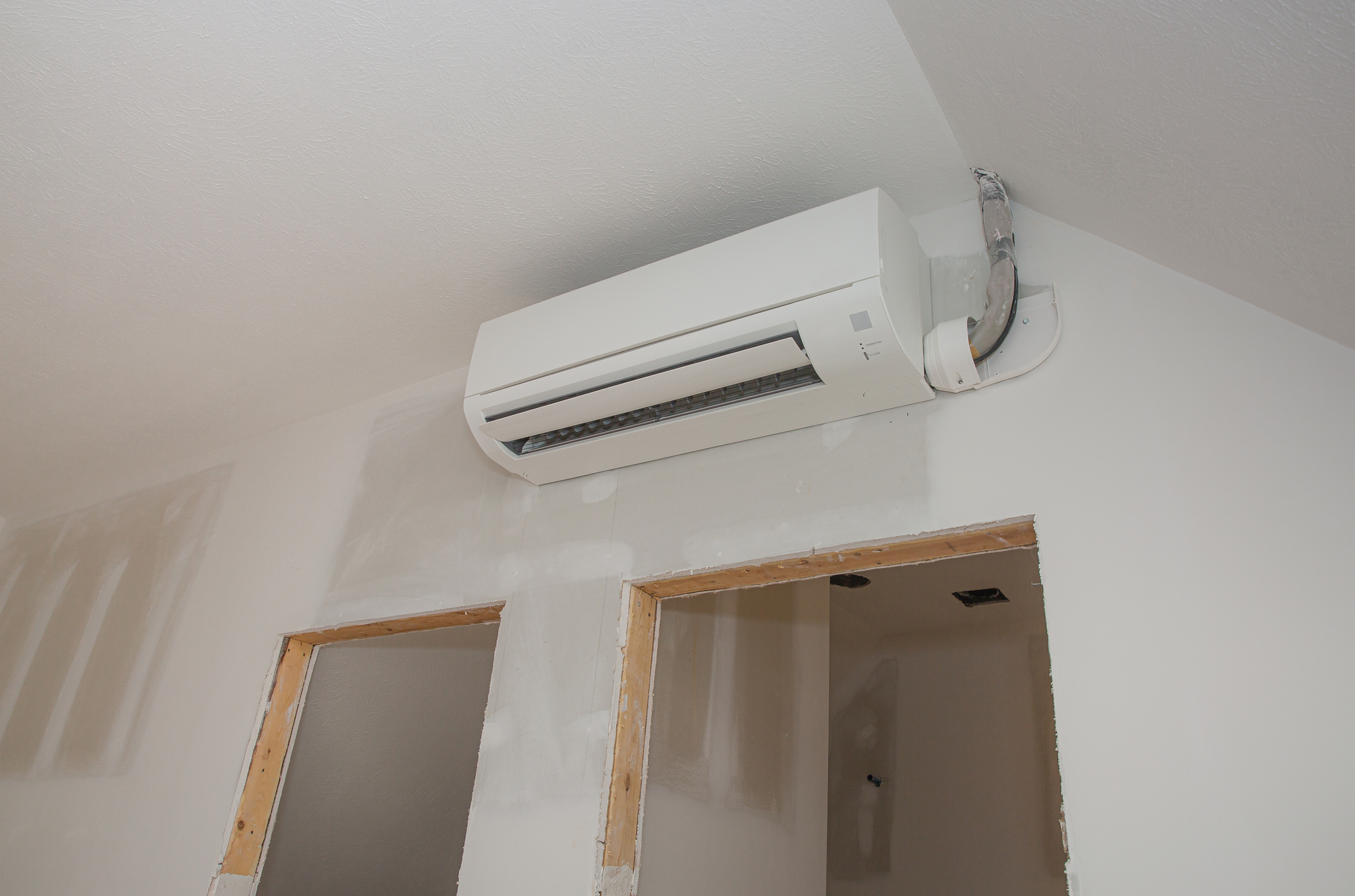 Ductless mini-split air conditioning unit installed in unfinished room